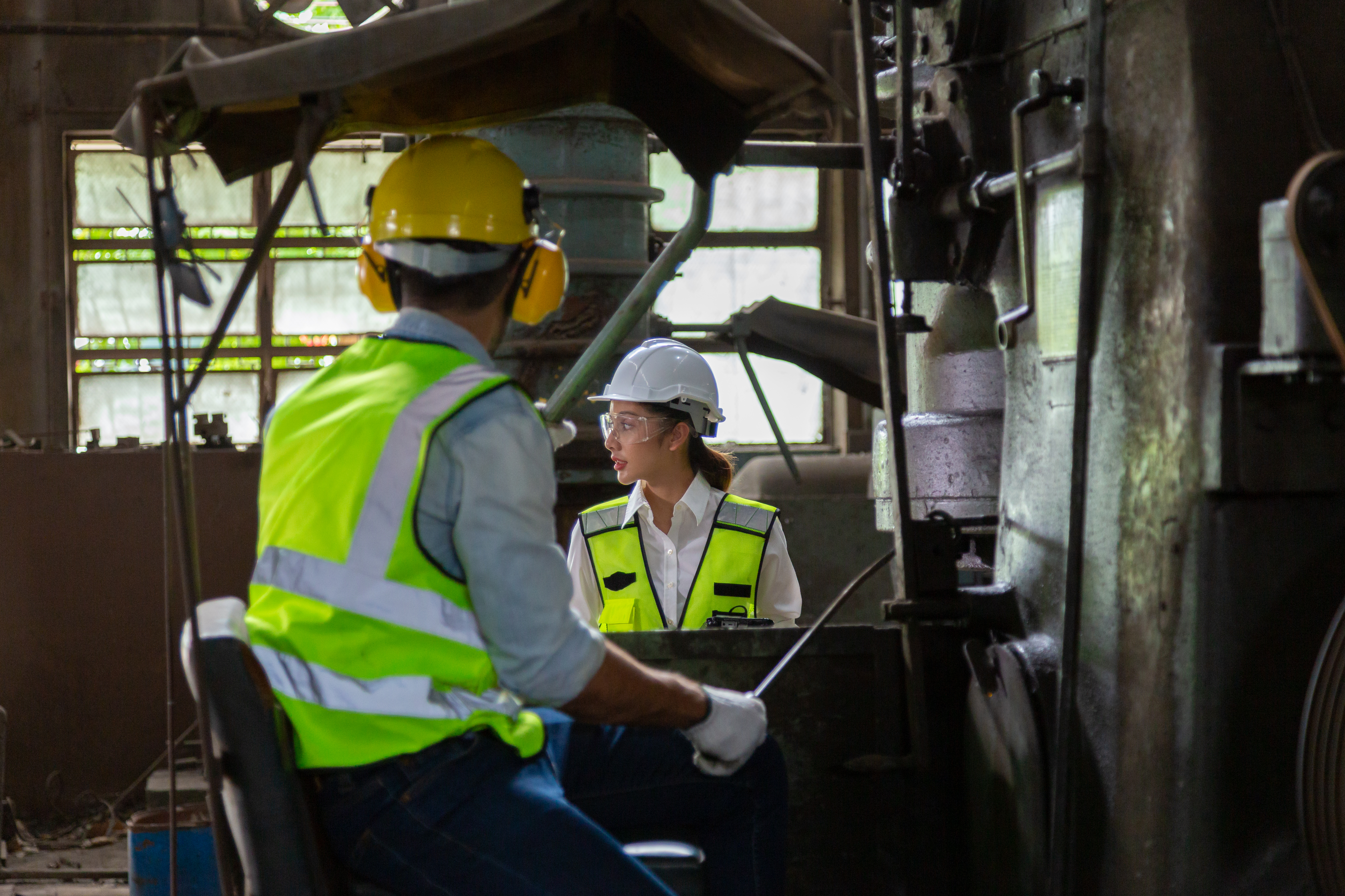 Two engineers in a steel mill Consult the size of the steel workpiece.